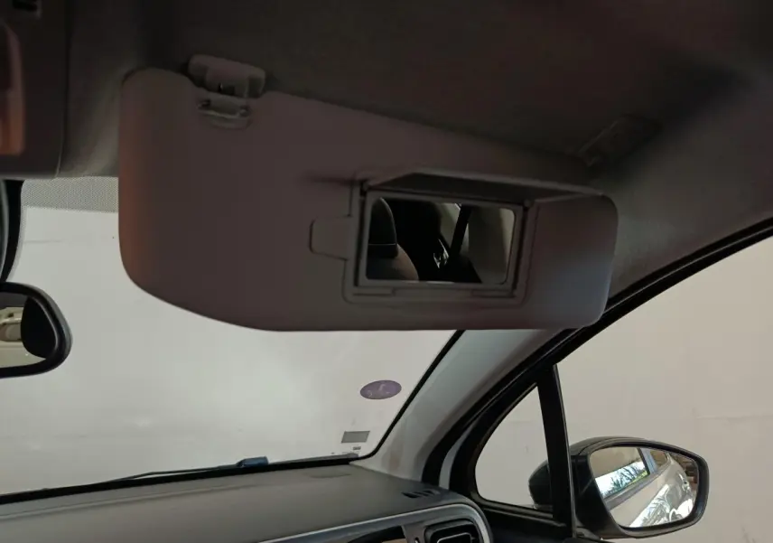 Intérieur de la Citroën C3 blanche, vue côté passager avec pare-soleil et miroir de courtoisie déployé.