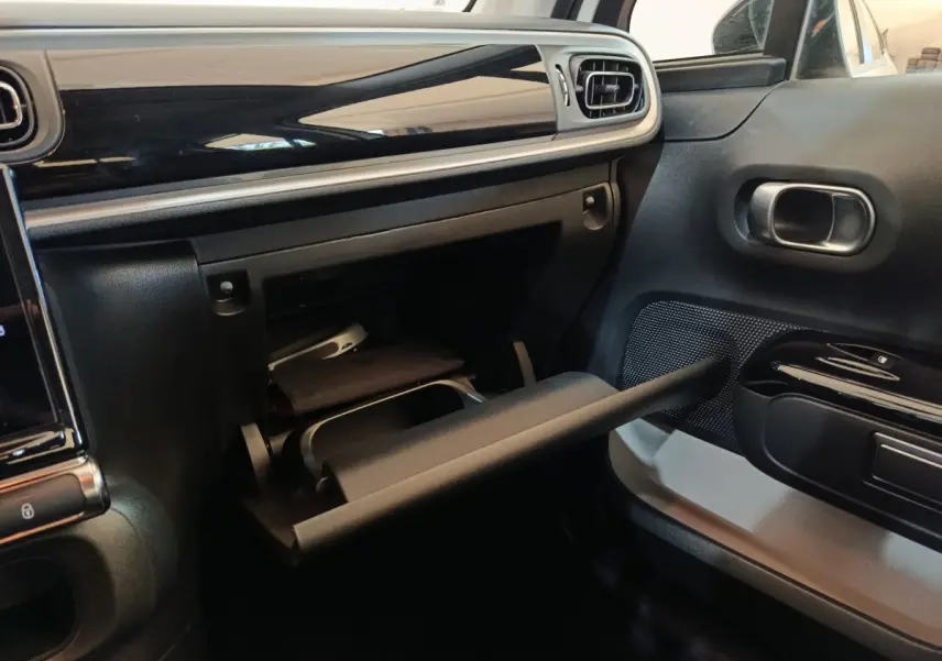 Intérieur de la Citroën C3 2021 blanc, vue côté passager sur la boîte à gants ouverte et tableau de bord noir brillant.