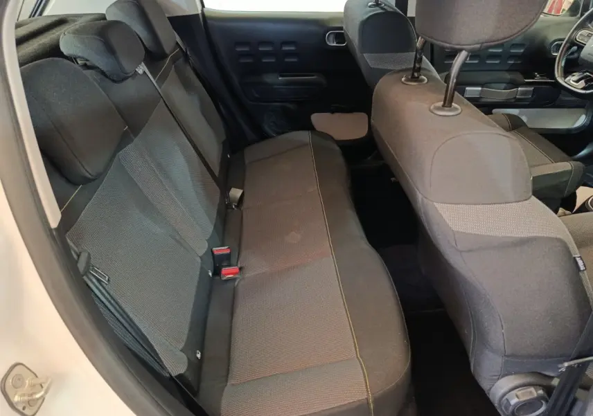 Vue intérieure côté gauche montrant la banquette arrière noire et les sièges avant d'une Citroën C3 blanche.