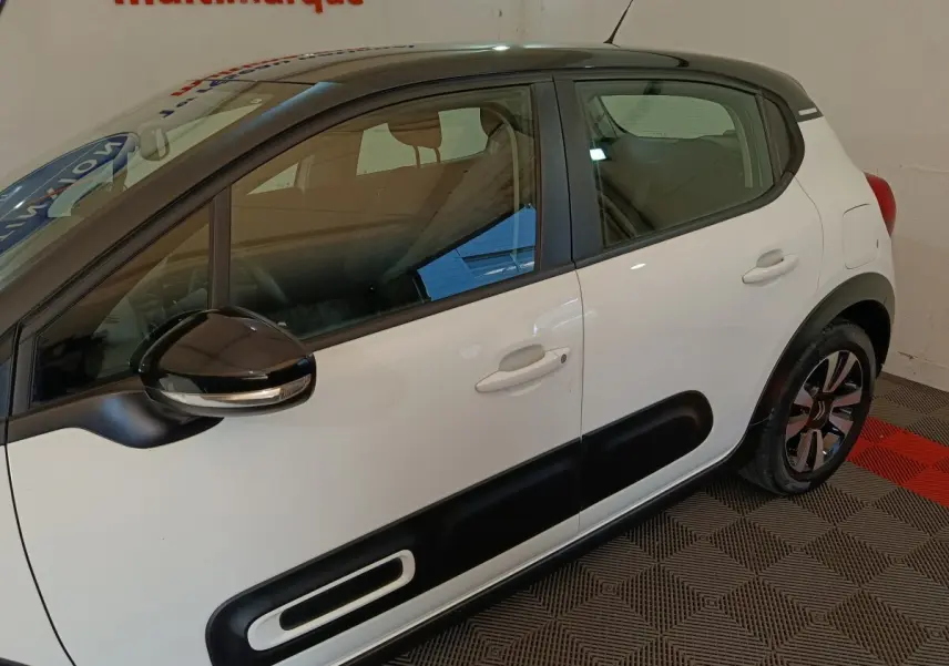 Vue latérale droite d'une Citroën C3 blanche 2021 avec protections noires sur les portes et rétroviseur noir brillant.