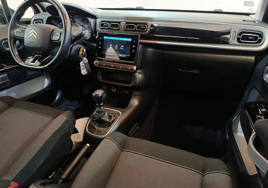 Vue intérieure côté conducteur de la Citroën C3 2021, tableau de bord noir avec écran tactile central et volant cuir.