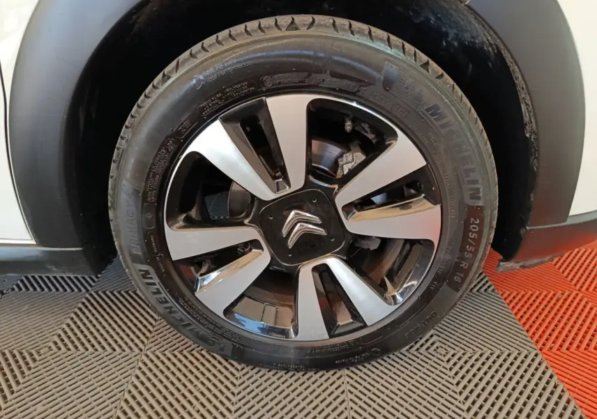 Gros plan sur la roue avant droite d'une Citroën C3 blanche, jante alliage bicolore avec logo Citroën central.