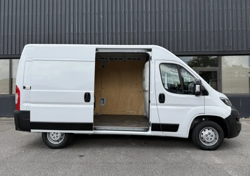 Peugeot Boxer Fourgon blanc vu de profil gauche avec porte coulissante ouverte montrant l’espace de chargement vide.
