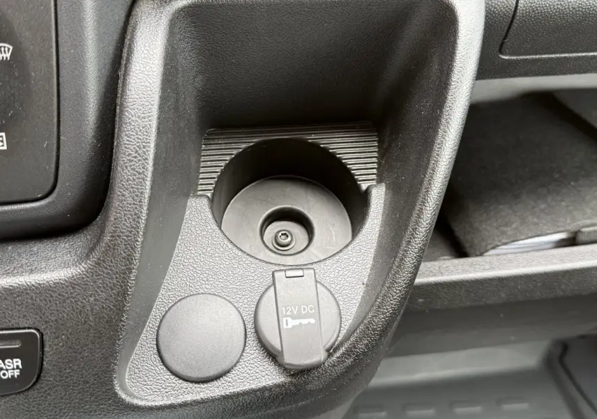 Gros plan sur la prise 12V et rangement noir dans l’habitacle du Peugeot Boxer Fourgon blanc, côté conducteur.