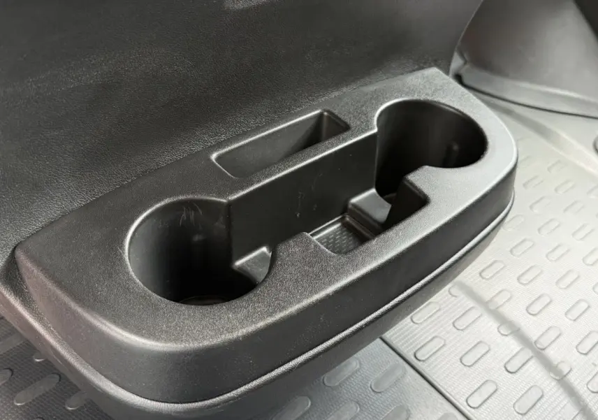 Gros plan sur le porte-gobelets noir côté passager du Peugeot Boxer Fourgon blanc, avec tapis caoutchouc gris en arrière-plan.