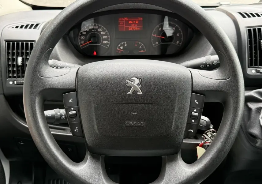 Vue rapprochée du volant noir multifonctions et du tableau de bord numérique du Peugeot Boxer Fourgon 2023.