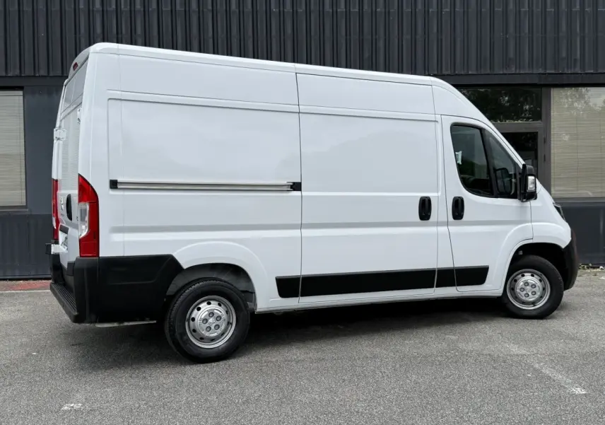 Vue de profil côté droit d’un Peugeot Boxer Fourgon blanc 2023 avec porte latérale coulissante et jantes acier.