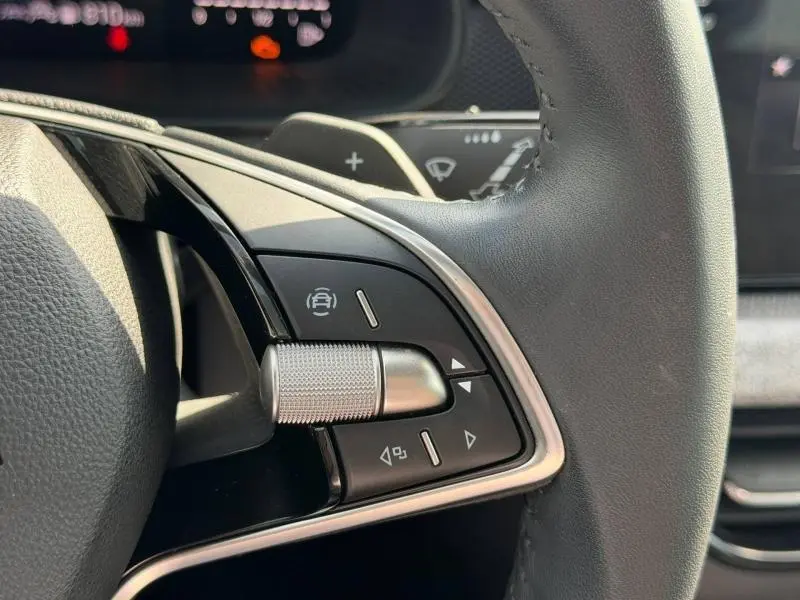 Gros plan sur les commandes multifonctions en aluminium et plastique noir du volant cuir d’une Skoda Scala 2025.