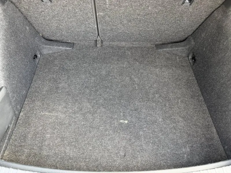 Coffre vu de dessus de la Skoda Scala noir Magic nacré, avec revêtement gris et banquette arrière rabattable visible.