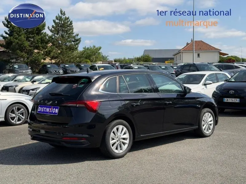 Vue 3/4 arrière droite d'une Skoda Scala noir Magic nacré avec jantes alu, stationnée en extérieur sur un parking multimarque.