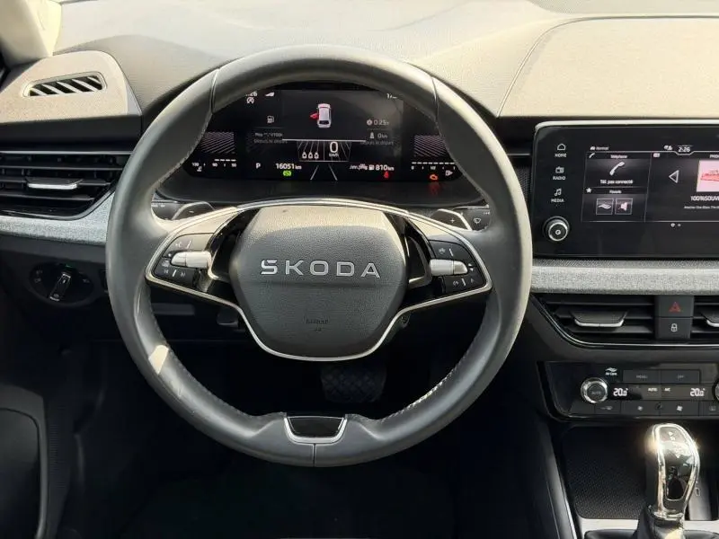 Vue intérieure centrée sur le volant cuir multifonction d'une Skoda Scala 2025 avec tableau de bord numérique et écran tactile.