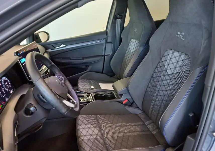 Vue intérieure côté conducteur de la Volkswagen Golf 1.5 eTSI R-Line 2025 avec sièges sport gris et tableau de bord digital.