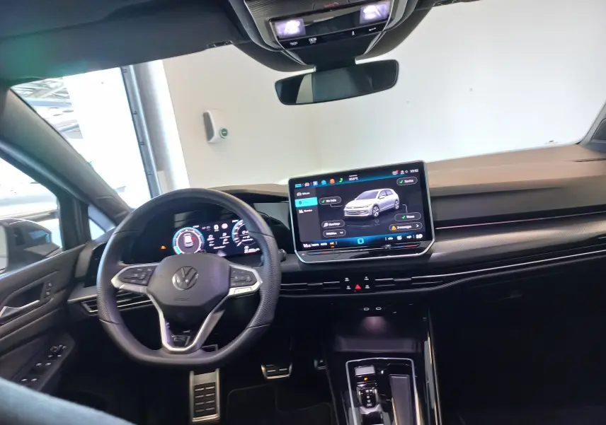 Vue intérieure du poste de conduite de la Volkswagen Golf 1.5 eTSI R-Line 2025 avec écran tactile et volant multifonction noir.