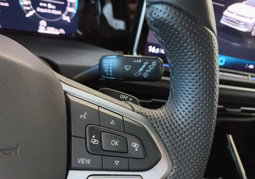Gros plan sur le volant en cuir perforé et les commandes multifonctions du Volkswagen Golf 1.5 eTSI 2025, intérieur moderne.