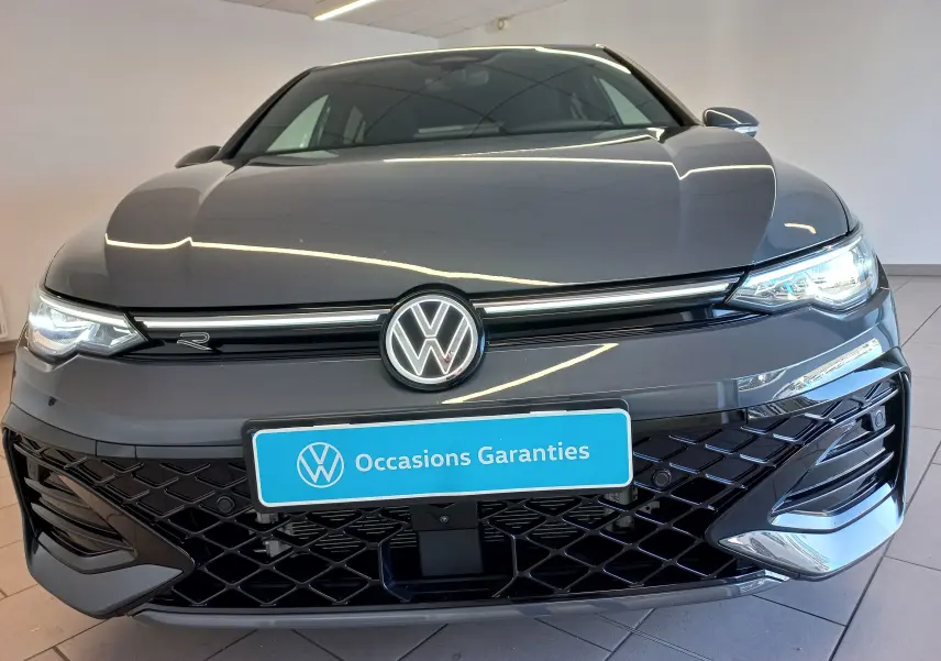Vue avant rapprochée de la Volkswagen Golf 1.5 eTSI R-Line gris dauphin avec calandre noire et phares LED allumés.