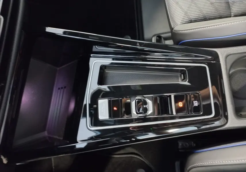 Vue rapprochée de la console centrale noire brillante de la Volkswagen Golf 1.5 eTSI R-Line avec commandes électroniques et sièges gris.