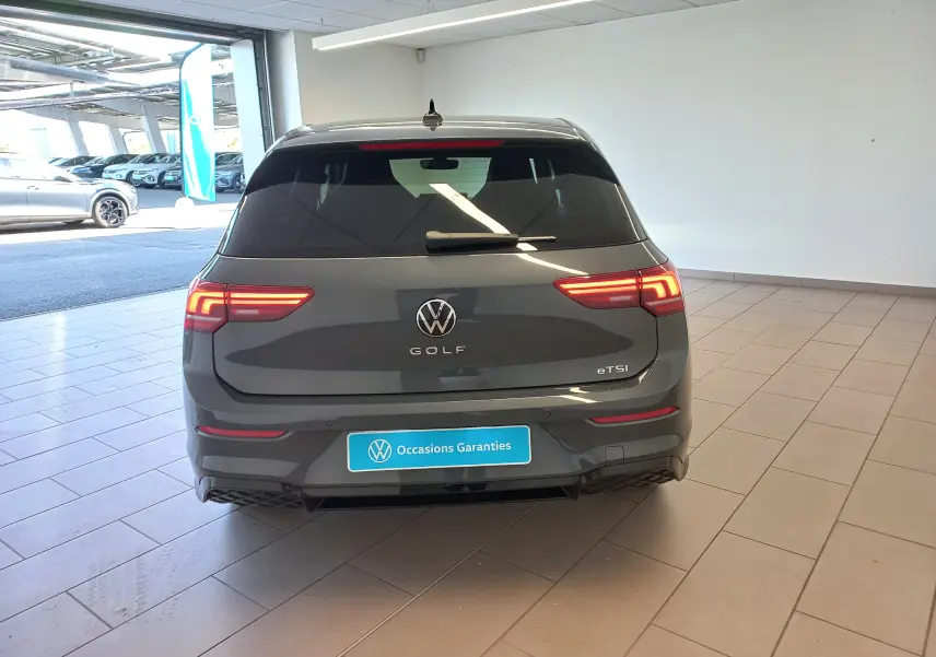 Vue arrière d'une Volkswagen Golf 1.5 eTSI gris dauphin avec feux LED allumés dans un showroom.