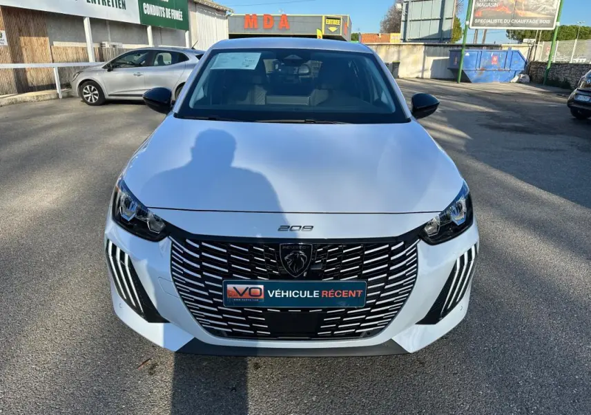 Vue avant d'une Peugeot 208 Hybrid 110 e-DCS6 Allure blanche, avec calandre noire distinctive et phares LED.