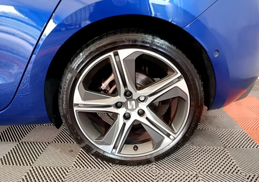 Gros plan sur la roue arrière droite d’une SEAT Leon bleu 2021 avec jante alliage cinq branches bicolore.