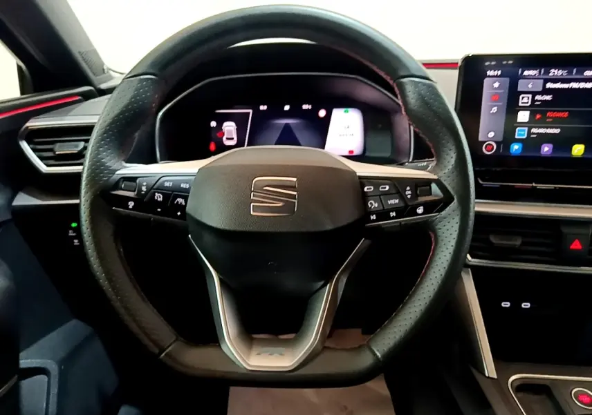 Vue frontale du volant cuir perforé noir de la SEAT LEON 1.5 eTSI avec tableau de bord numérique et écran tactile.