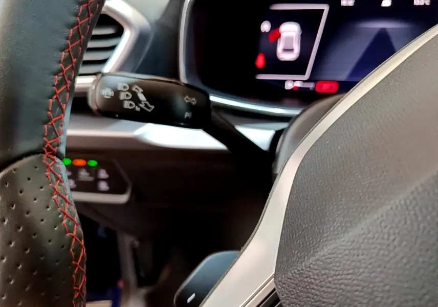 Gros plan sur le volant cuir noir avec surpiqûres rouges et le tableau de bord numérique du SEAT Leon 1.5 eTSI 2021.