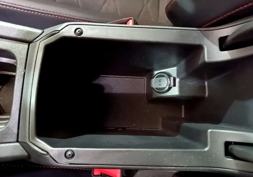 Vue rapprochée de la console centrale noire avec prise 12V du SEAT Leon 1.5 eTSI 150 DSG FR 2021.