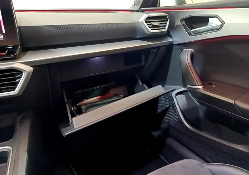Intérieur SEAT Leon 1.5 eTSI 2021, vue côté passager sur boîte à gants ouverte et détails du tableau de bord noir.