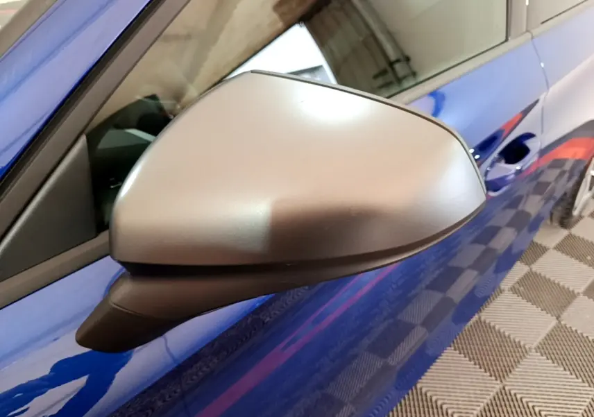 Rétroviseur côté gauche gris mat sur SEAT Leon bleu, vue rapprochée du profil avant droit.