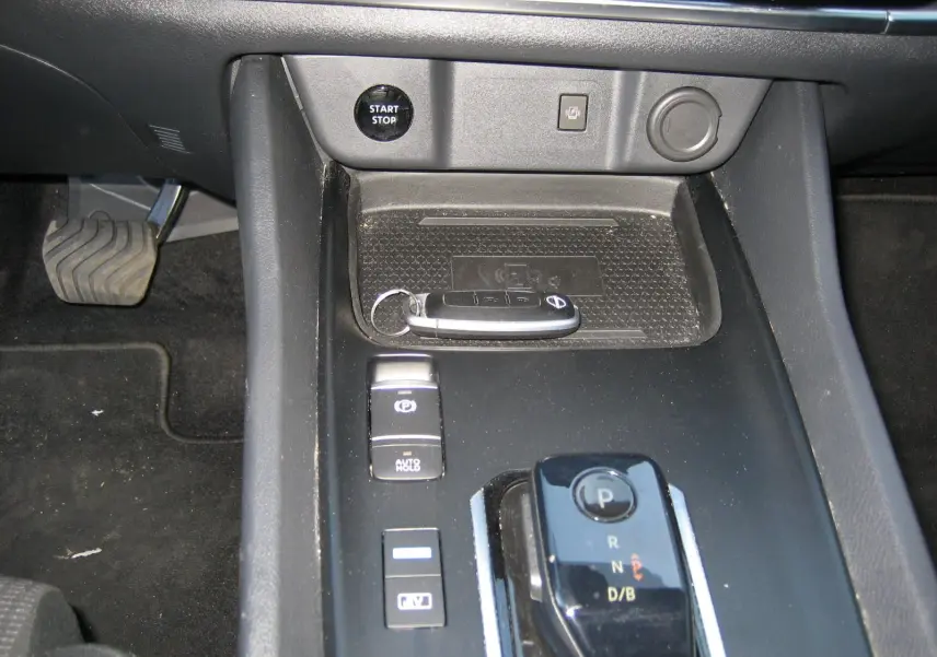 Vue rapprochée de la console centrale noire du Nissan Qashqai blanc nacré, avec clé, bouton start/stop et levier de vitesse automatique.