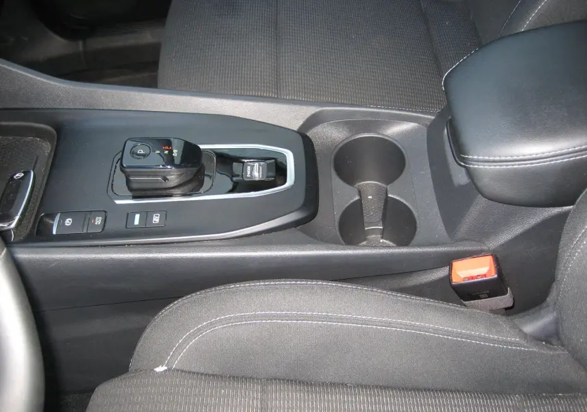 Vue rapprochée de la console centrale noire du Nissan Qashqai 2024 avec levier de vitesse automatique et porte-gobelets.