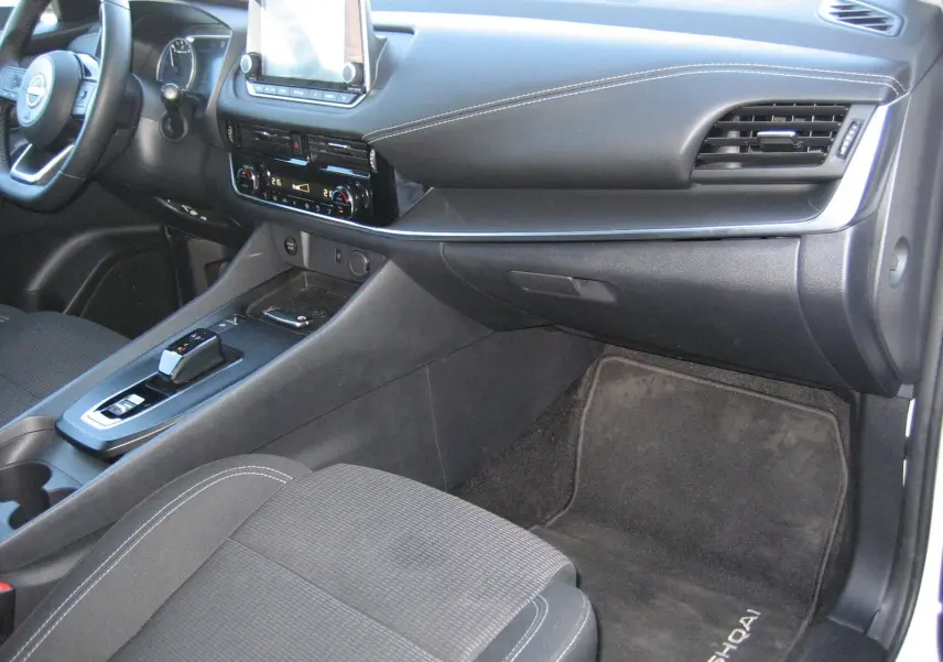 Vue intérieure côté passager du Nissan Qashqai 2024, montrant la console centrale et le tapis avec logo Qashqai.