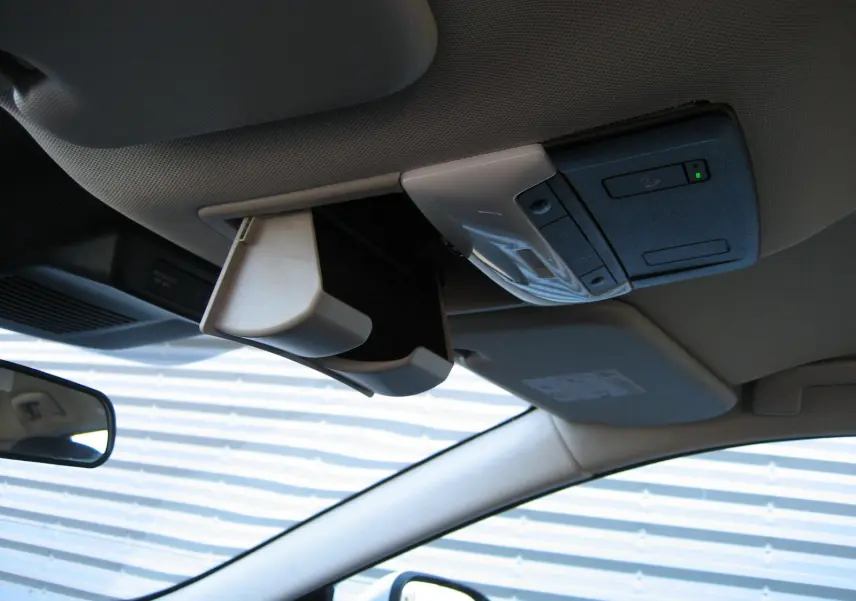 Vue intérieure du plafond du Nissan Qashqai blanc nacré 2024, avec rangement lunettes ouvert et commandes intégrées.