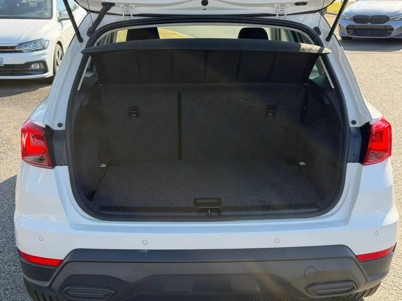 Vue arrière du coffre ouvert d'un SEAT Arona blanc Candy avec toit noir, montrant l'espace de chargement vide.