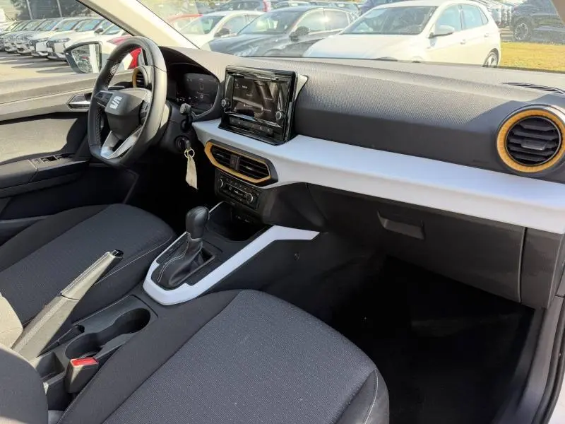 Intérieur avant droit du SEAT Arona 2025 avec tableau de bord blanc, volant cuir multifonction et sellerie tissu gris.