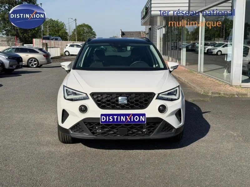Vue de face d'un SEAT Arona blanc Candy avec toit noir, calandre noire et feux LED marqués.