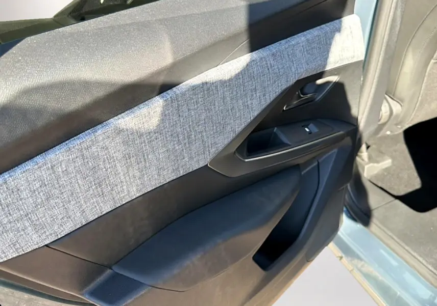 Vue rapprochée de la porte avant gauche bleu clair du Peugeot 3008 1.2 hybrid 145 allure avec habillage tissu gris.