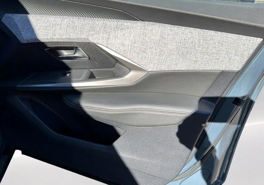 Détail de la porte avant droite du Peugeot 3008 bleu 2025, avec garniture tissu gris et accoudoir noir.