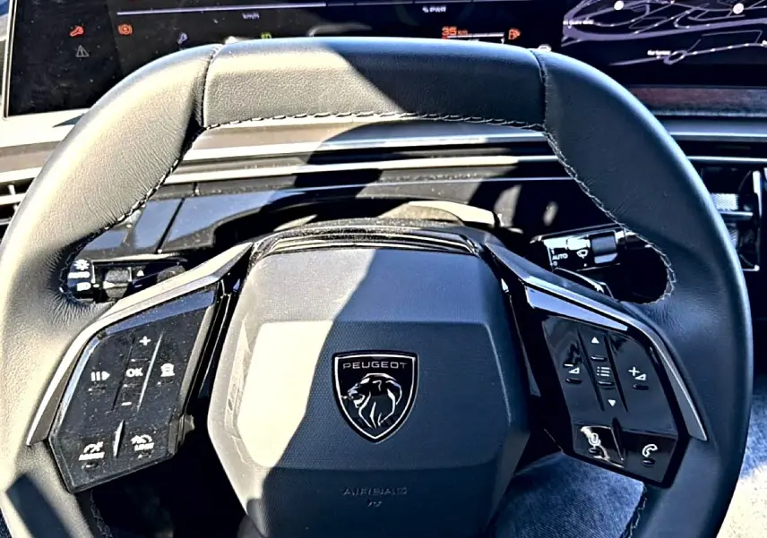 Vue rapprochée du volant cuir noir multifonction du Peugeot 3008 2025 avec logo lion central et commandes intégrées.