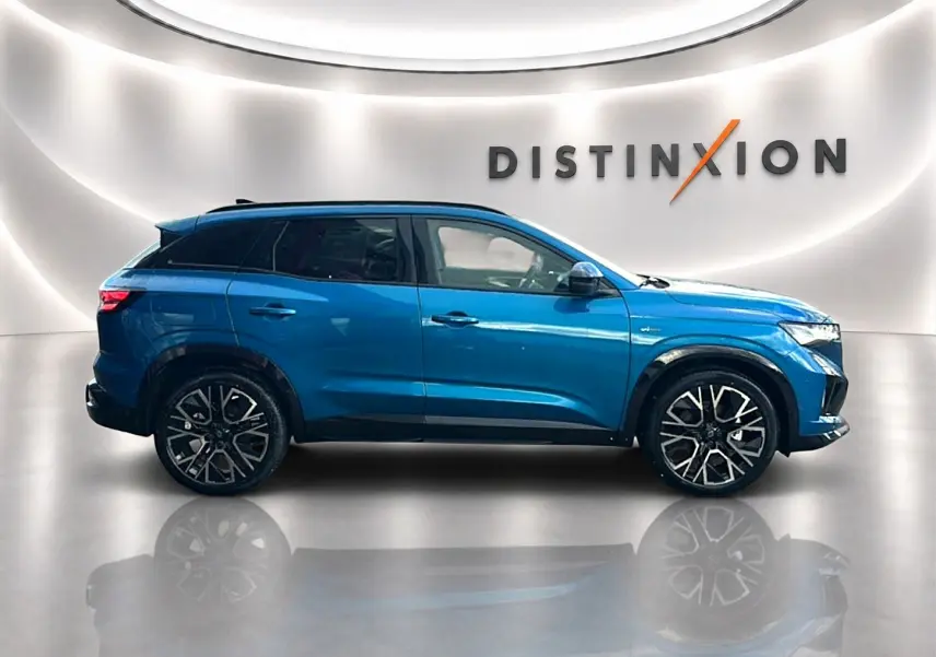 Vue de profil côté gauche du Renault Austral bleu outremer avec jantes alliage et toit noir dans un showroom lumineux.