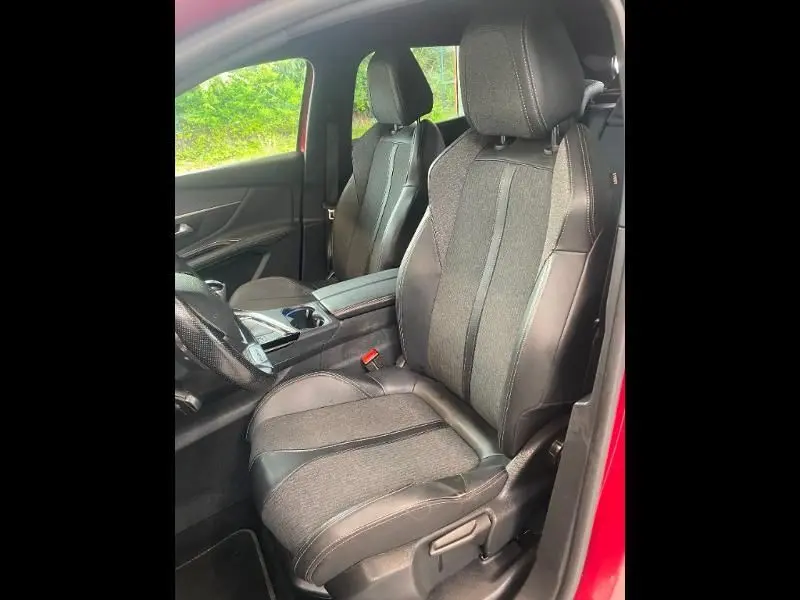 Vue intérieure côté conducteur du Peugeot 3008 rouge de 2018, sièges tissu et cuir noir avec coutures contrastées.