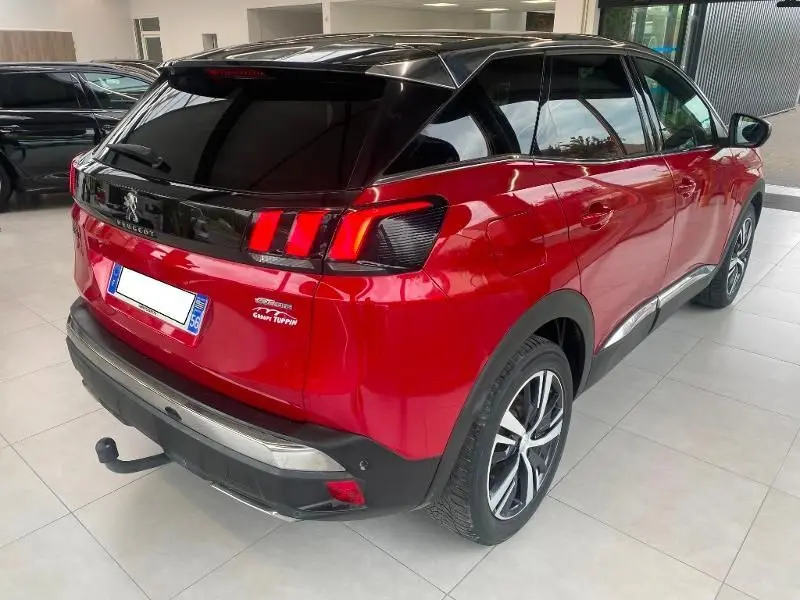 Vue 3/4 arrière droite d'un Peugeot 3008 rouge de 2018 avec toit noir brillant et feux arrière à griffes distinctifs.