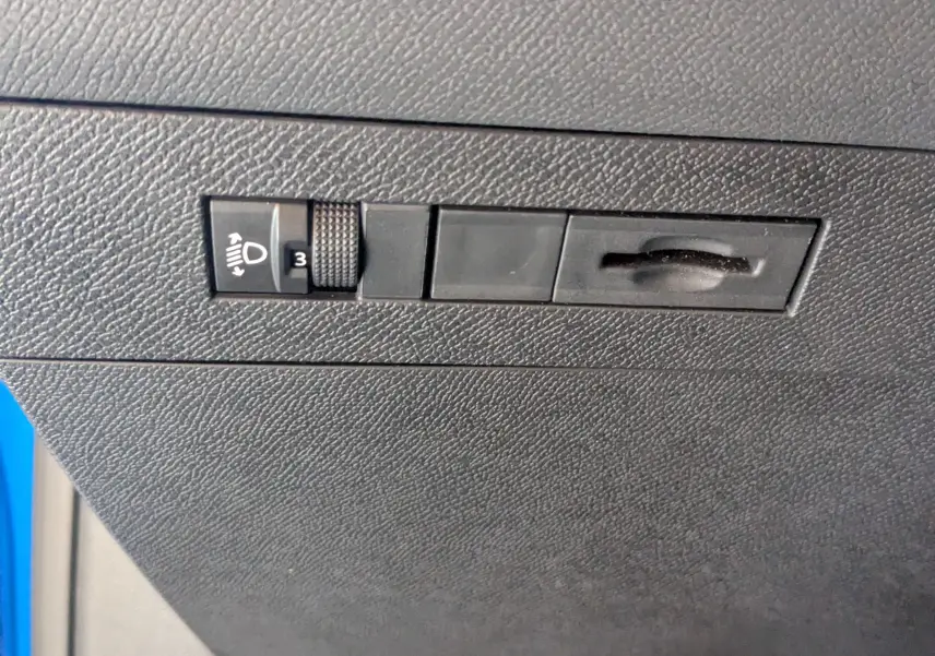 Gros plan sur le réglage de hauteur des phares à gauche du tableau de bord d'une Opel Astra bleu 2022.