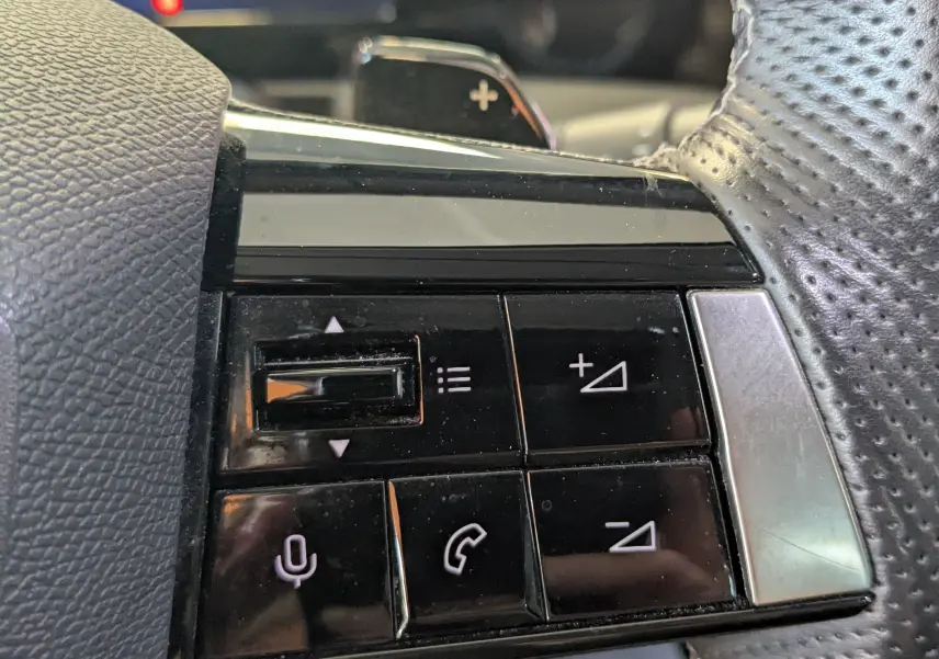 Gros plan sur les commandes noires au volant en cuir perforé de l'Opel Astra 1.5D 130ch BVA8 Elegance 2022.