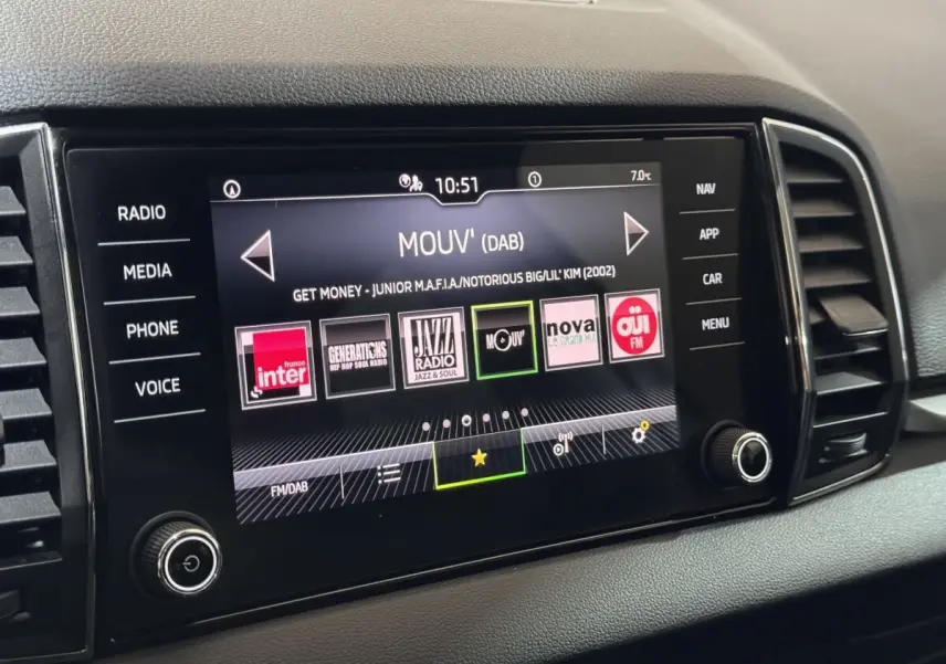 Écran tactile central du tableau de bord du Skoda Karoq blanc, affichant les stations radio numériques.