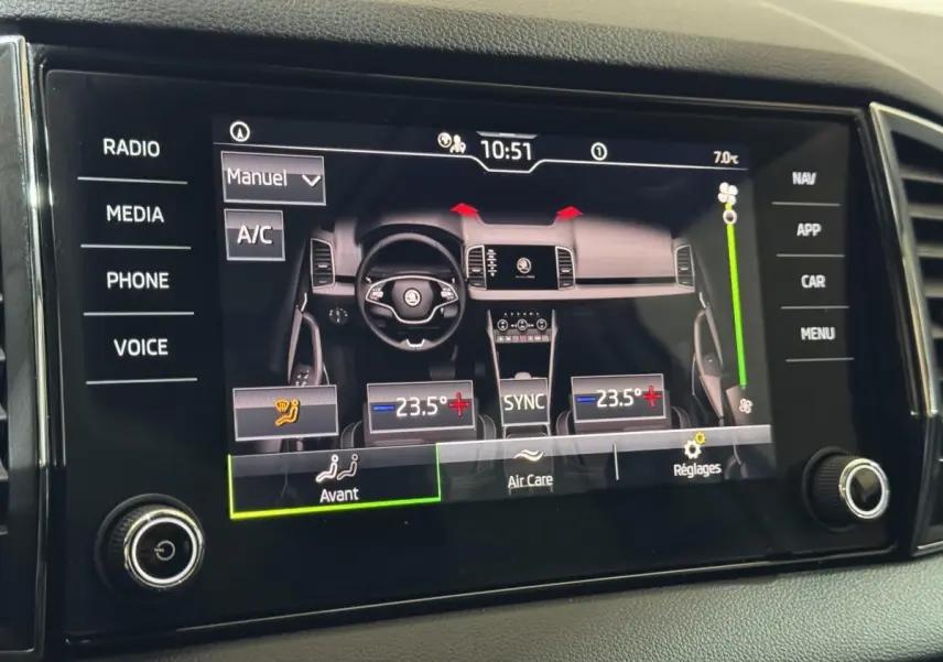 Écran tactile central affichant la climatisation bi-zone et vue stylisée du tableau de bord du Skoda Karoq blanc.