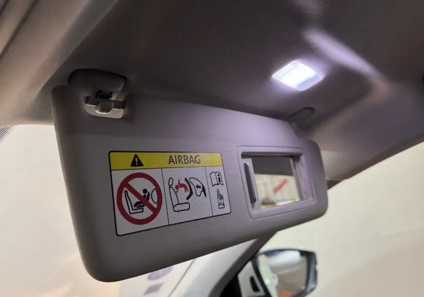Détail du pare-soleil côté conducteur avec miroir éclairé dans l'habitacle clair d'un Skoda Karoq blanc.