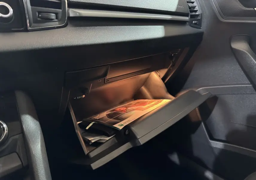 Gros plan sur la boîte à gants ouverte côté passager du Skoda Karoq 1.5 TSI blanc, intérieur noir.