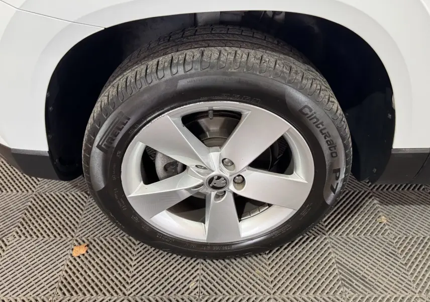 Gros plan sur la roue avant droite blanche d’un Skoda Karoq avec jante argentée à cinq branches.