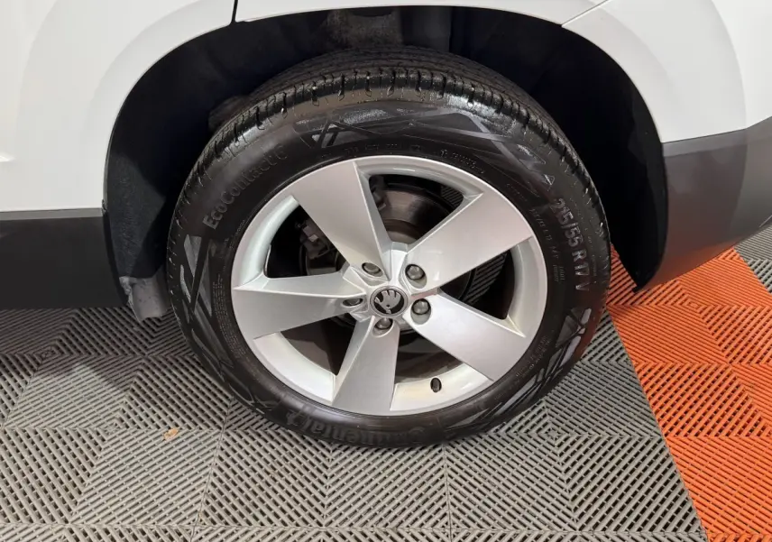 Gros plan sur la roue avant droite d'un Skoda Karoq blanc, avec jante alliage cinq branches et pneu Continental.