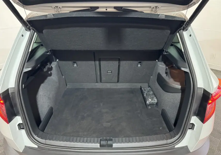 Coffre ouvert vu de l'arrière d'un Skoda Karoq blanc 2021, espace de chargement propre et spacieux.